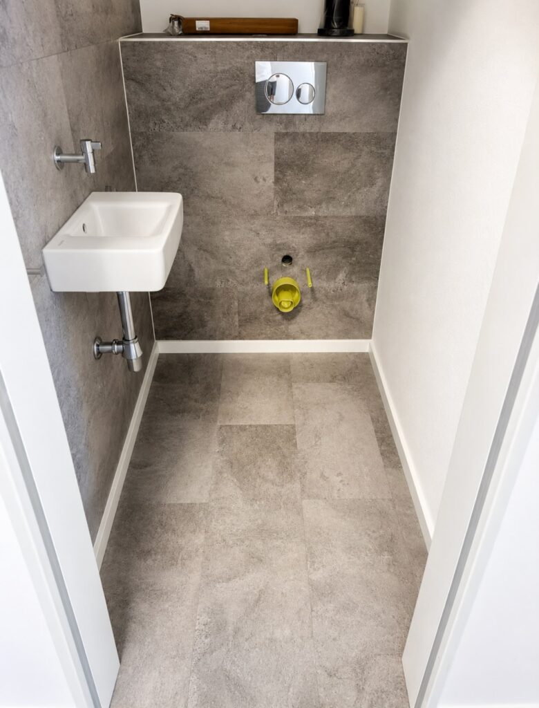 Modernes Gäste-WC mit Vinylboden und Wandverkleidung in Dobel – renoviert von Ejupi Trockenbau & Renovierung.